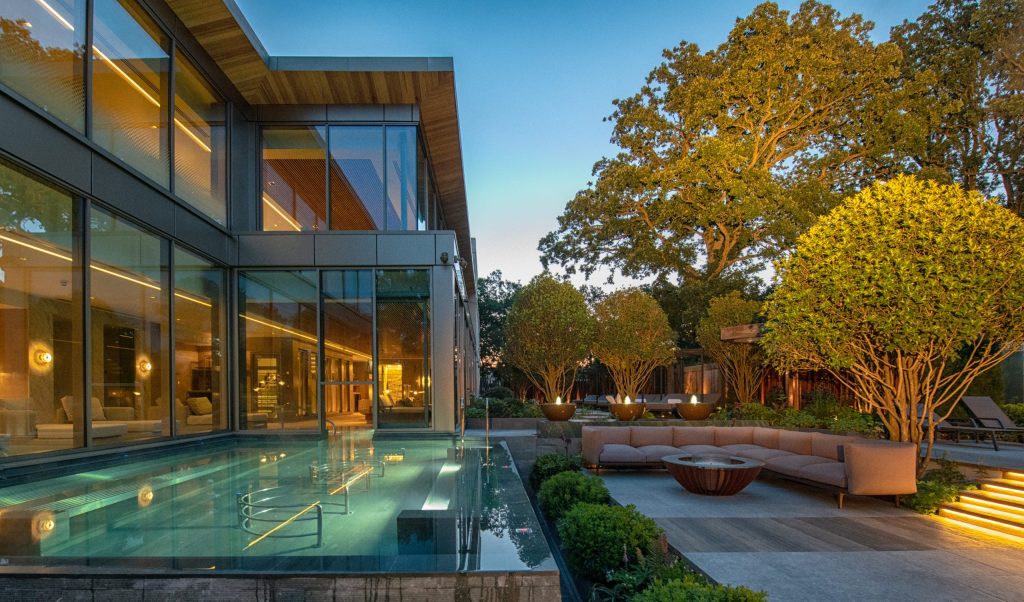 Modern spa exterior featuring a glass pool, lounge area with comfortable seating, and beautifully landscaped trees.