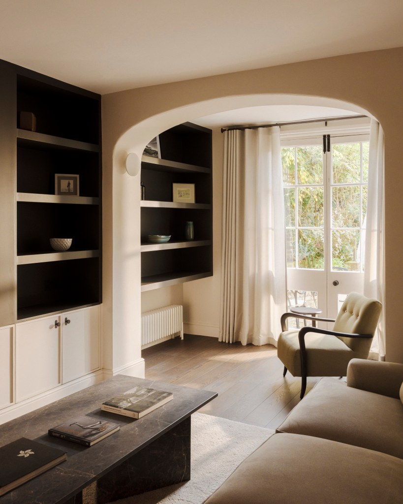 Cozy interior living space featuring a soft, neutral color palette, a stylish coffee table, and large windows with curtains, providing natural light.