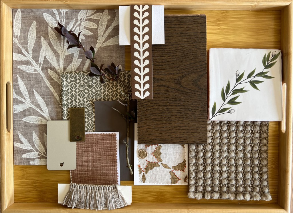 A collection of fabric swatches, wood samples, and decorative elements arranged on a wooden tray, showcasing various textures and earthy colors for interior design inspiration.