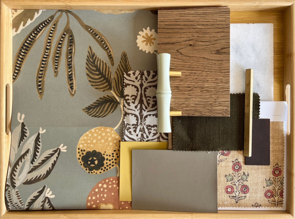 A wooden tray displaying a variety of material samples including patterned wallpaper, wood finishes, and fabric swatches, essential for interior design inspiration.
