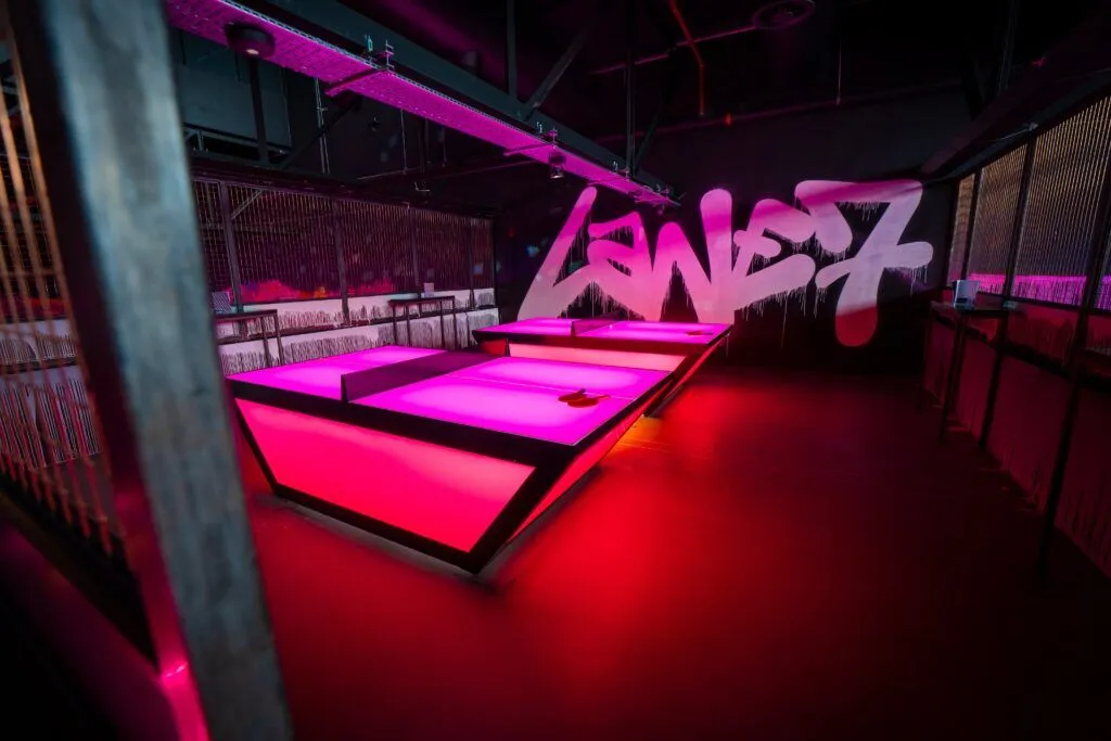 Interior of Lane7 in Manchester featuring vibrant pink lighting and urban graffiti, showcasing a stylish and playful atmosphere.