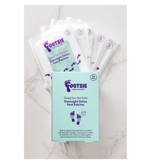 A box of Footsie Overnight Detox Foot Patches with several individual patches visible, designed for soothing foot care during sleep.