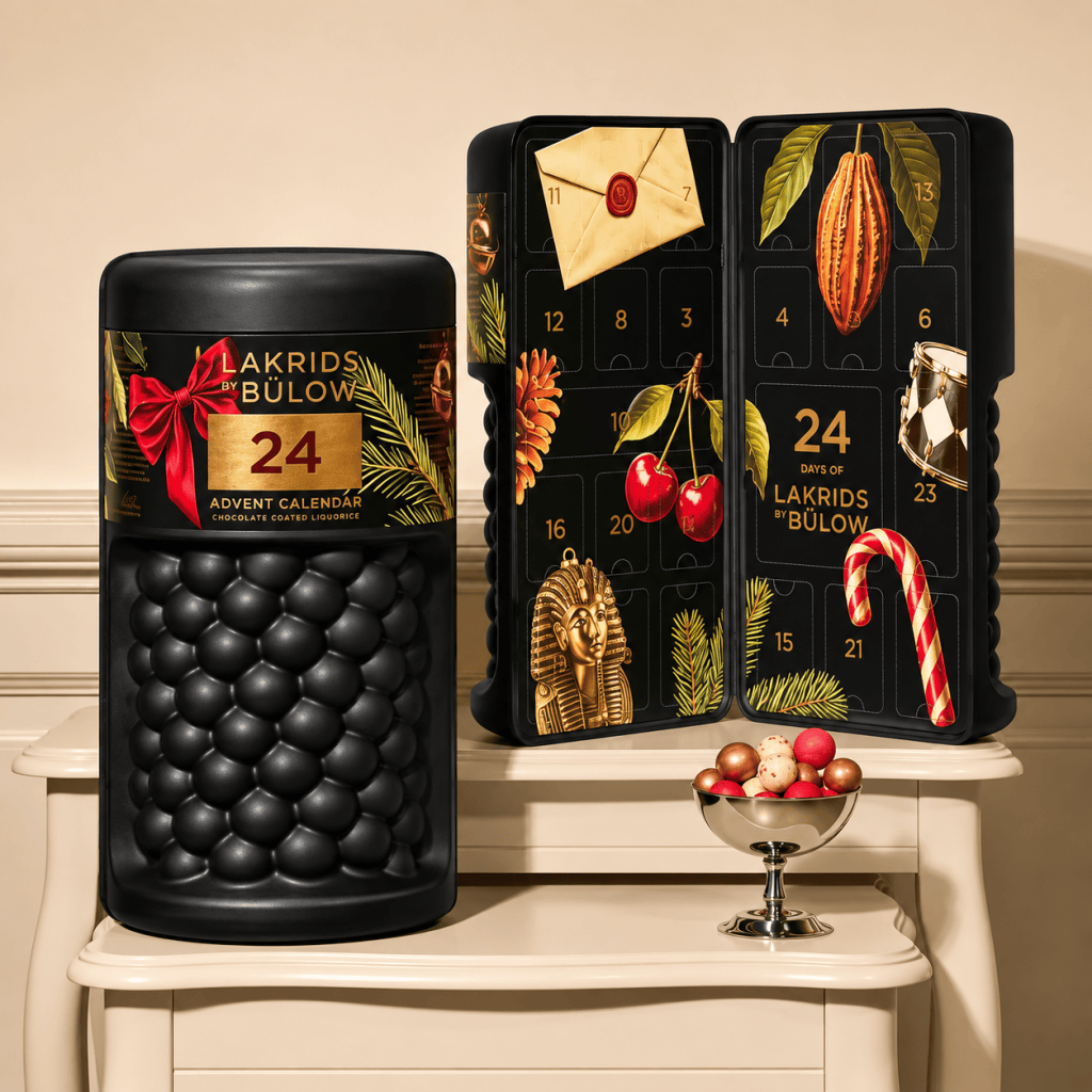 Lakrids by Bülow chocolate-covered liquorice advent calendar featuring 24 festive compartments, decorated with seasonal imagery like cherries, cocoa pods, and a candy cane.