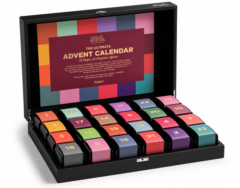 A wooden advent calendar featuring 24 compartments, each labeled with a number from 1 to 24, designed to hold organic spices. The calendar has a colorful design with a prominent label stating 'The Ultimate Advent Calendar' and details about discovering various spices. It is closed and displayed from a frontal view.